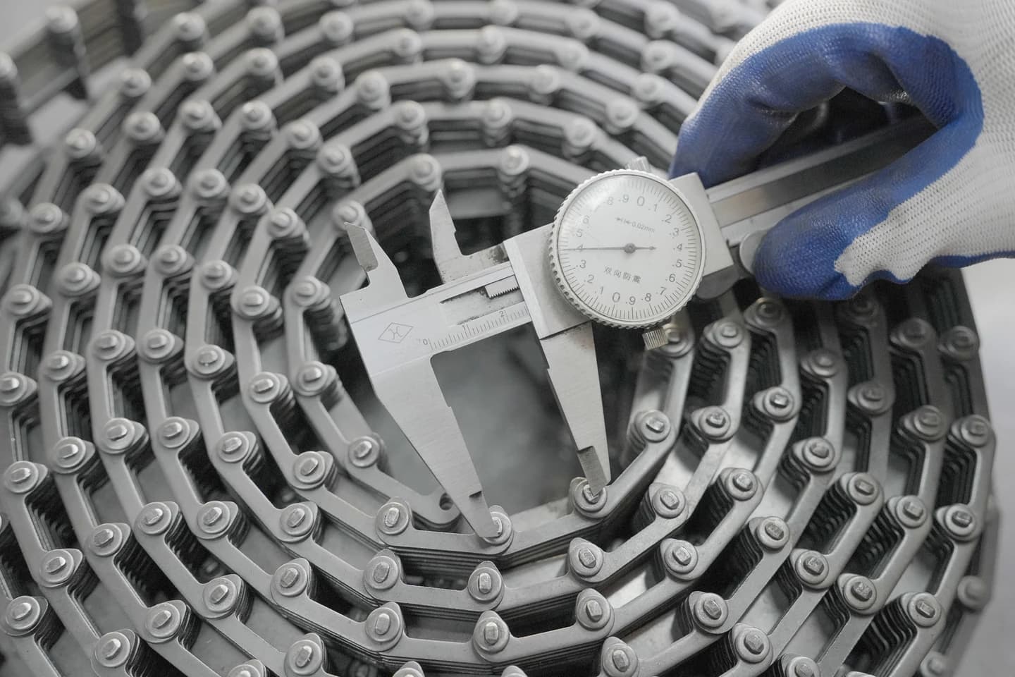 Dial calliper positioned across a feature on a coiled conveying chain