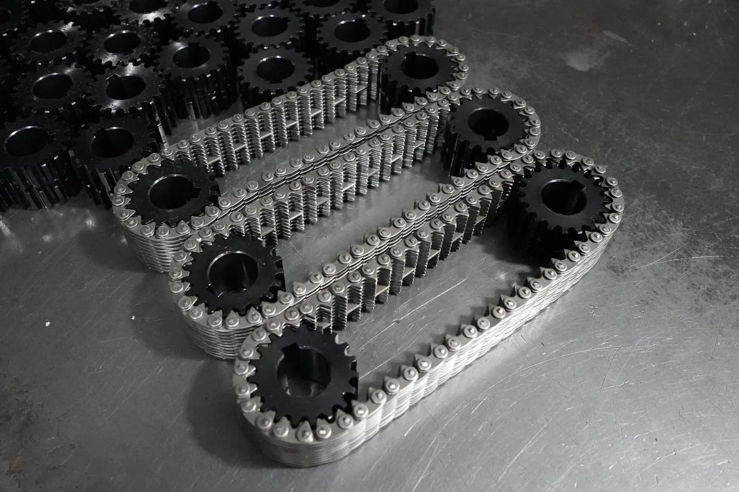 Silent chains and matched sprockets arranged on a metal workshop surface