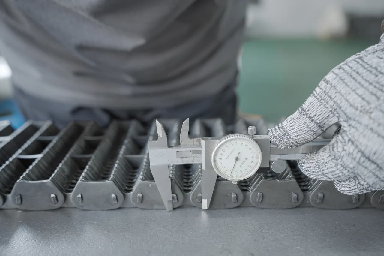 Technician checking chain dimensions with a caliper during quality inspection