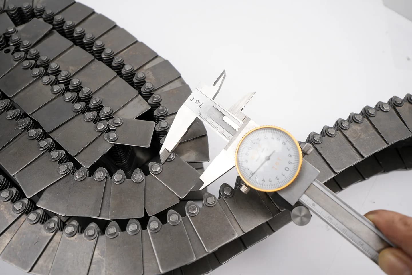 Dial calliper positioned across a chain during dimensional inspection